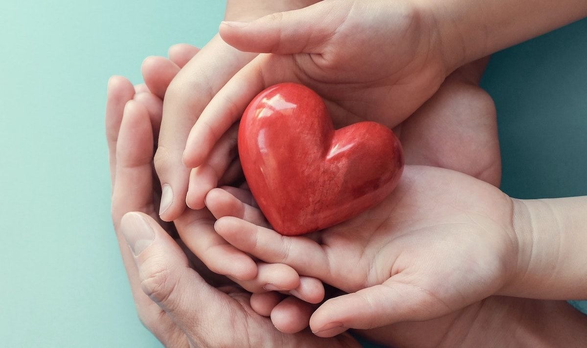 Hände unterstützen sich und halten Herz